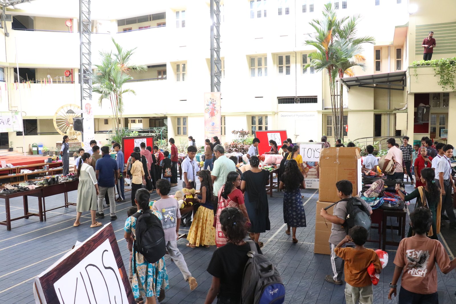 Families browse tables of clothing, shoes, toys, and other goods at the school charity fair
